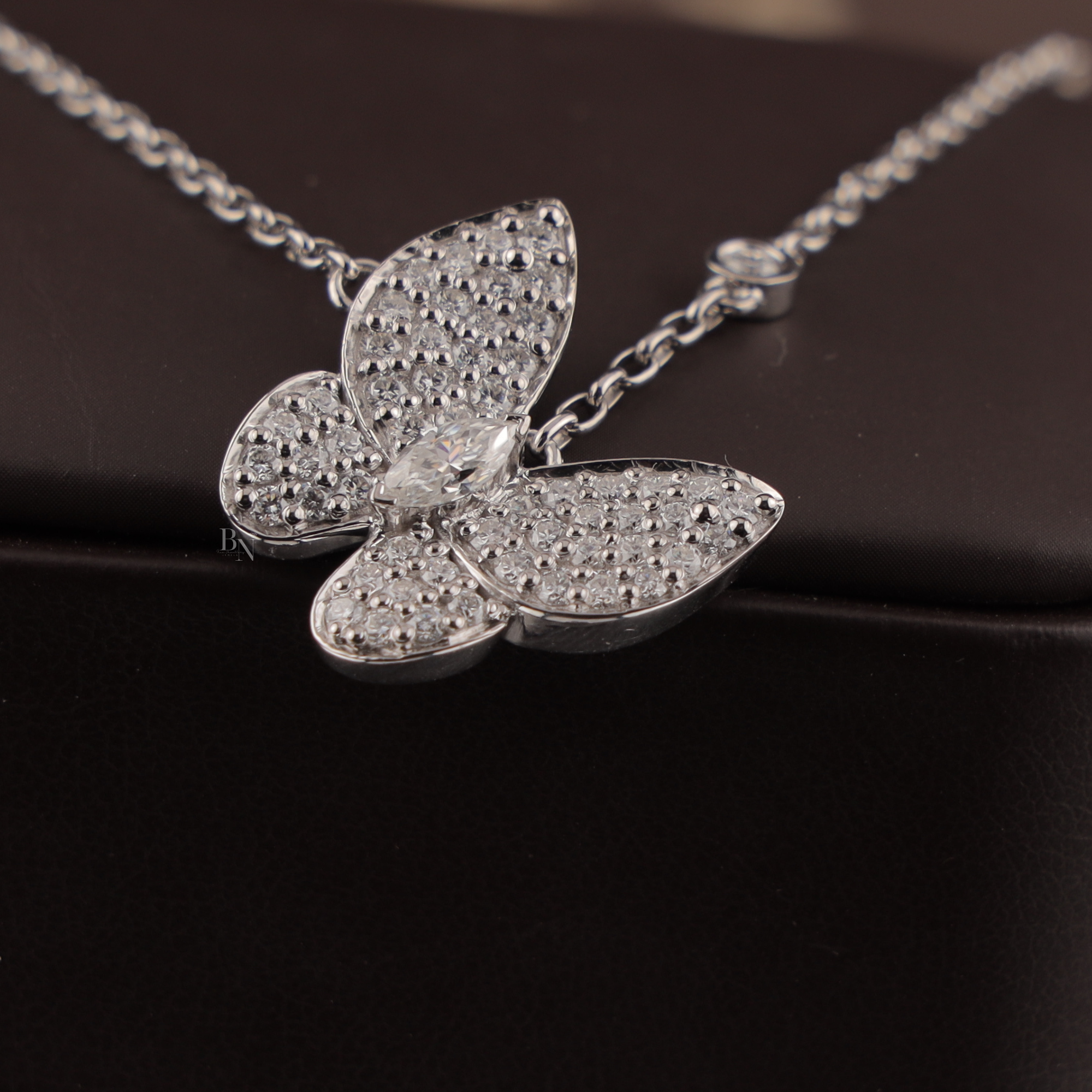 Dainty 1.00 CTW butterfly pendant necklace in 14k white gold featuring a marquise cut lab diamond center stone with brilliant pavé set lab diamonds on the wings, held in a hand to show scale and fine craftsmanship.