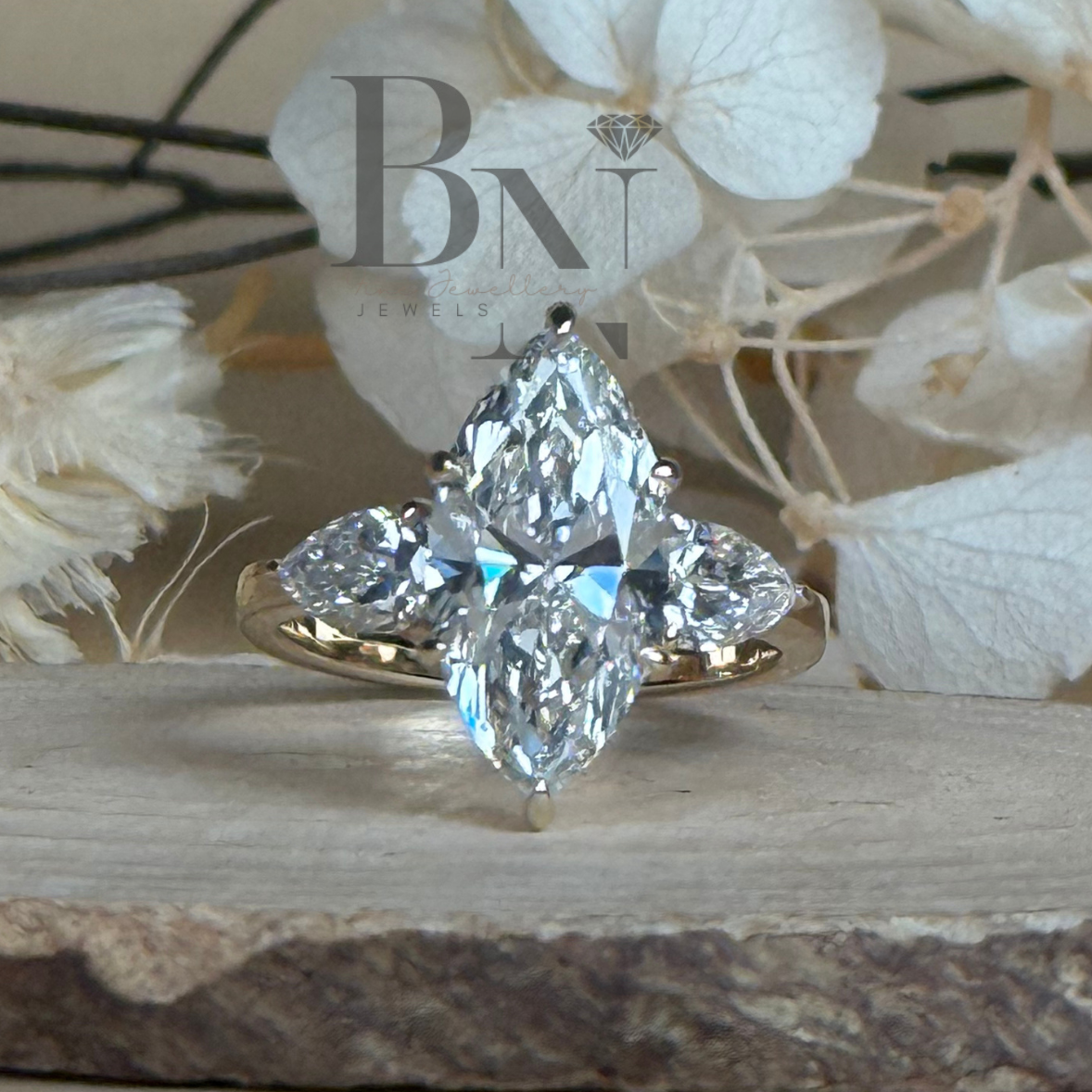 3 carat elongated marquise lab grown diamond engagement ring in 14k  gold three stone setting with pear side stones and a hidden halo detail shown from a front-facing angle on a neutral background to showcase Type IIa diamond brilliance.