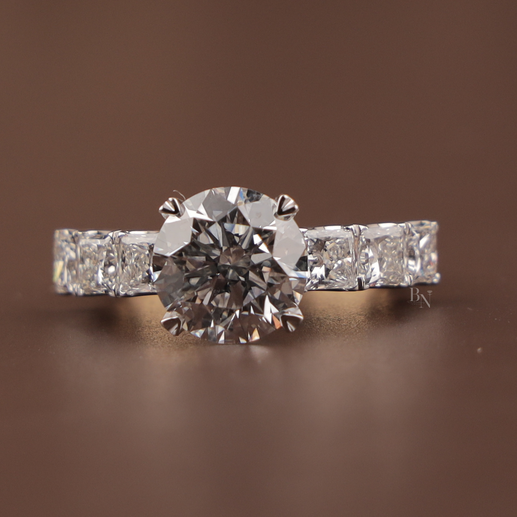 3 carat round brilliant cut lab grown diamond engagement ring with compass prongs and princess cut diamond accents on a 14k yellow gold band.