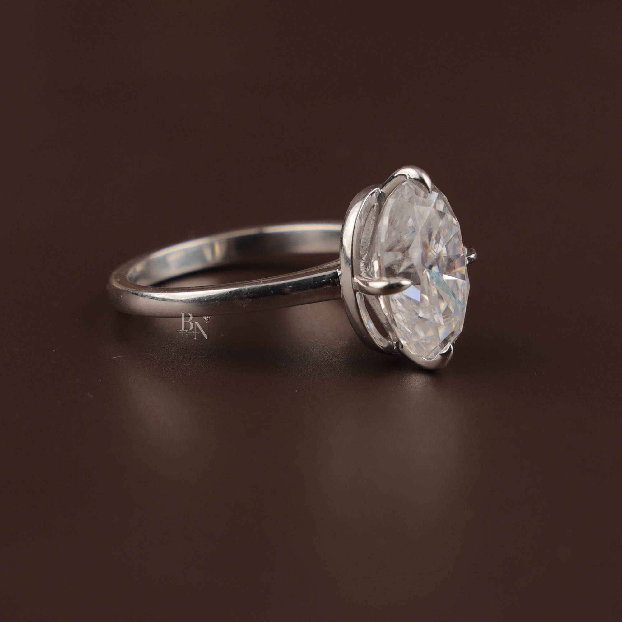7.00 carat oval moissanite solitaire ring in 14k white gold. The stone features a crushed ice cut with intense rainbow fire and kaleidoscopic sparkle, set in a minimal six-prong high-profile mount.