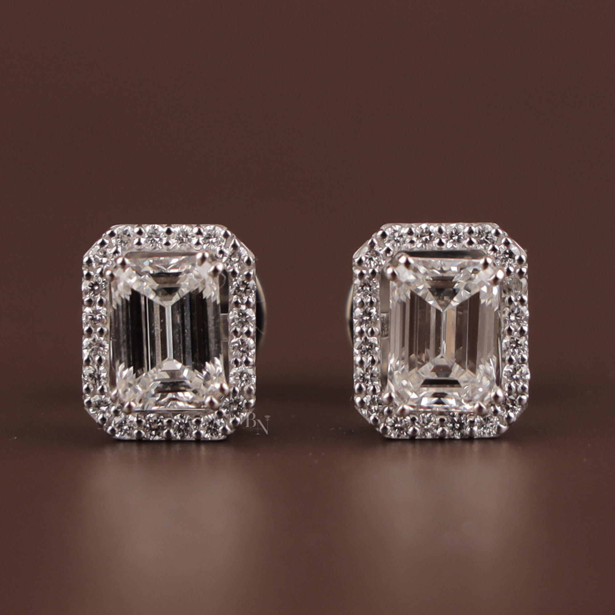 3 carat total weight emerald cut lab grown diamond stud earrings in 14k white gold with a convertible pave halo jacket showing secure screw back posts and crisp step-cut facets on a dark background.