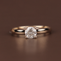 Close up of a round brilliant cut lab grown diamond engagement ring in yellow gold featuring a hidden halo setting and micro pave diamonds along the polished band for a classic bridal aesthetic