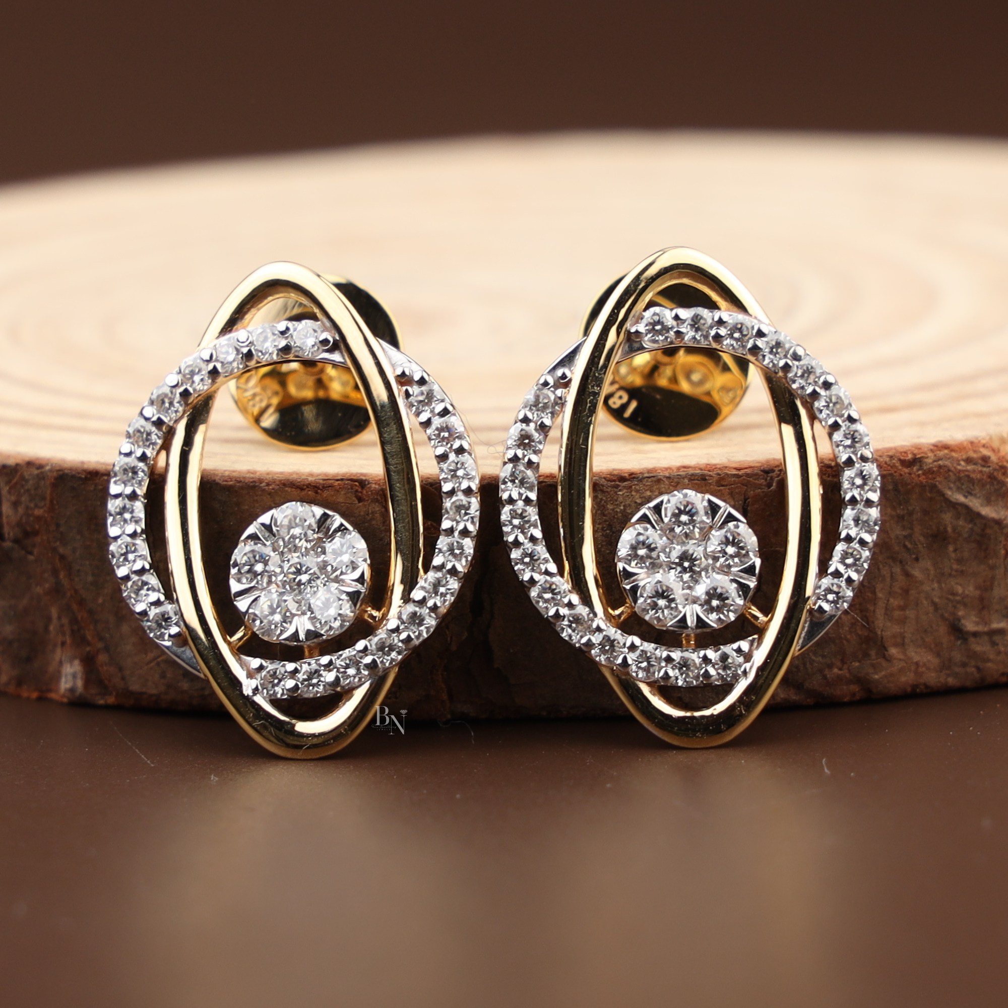 Pair of modern abstract stud earrings featuring interlocking 14k yellow gold and white gold oval bands with a center round lab grown diamond cluster and pave halo.