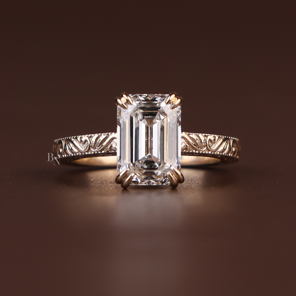 3 carat emerald cut lab grown diamond engagement ring with ornate hand-engraved vintage style band in 14k gold, fine bridal jewelry macro view.