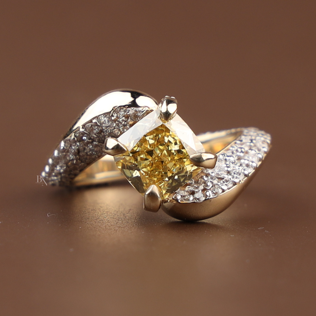 Side profile of a 2 carat fancy yellow cushion cut lab grown diamond engagement ring featuring a unique bypass band pavé set with white diamonds in 14k gold.