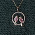 Macro shot of two pink pear cut lab grown diamonds shaped as birds inside a circular pavé diamond halo pendant in 14k white gold on a dainty chain.
