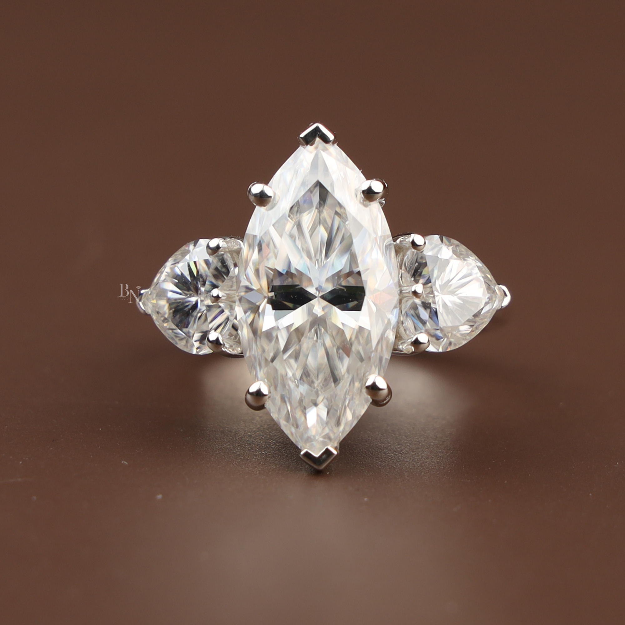 5.50 carat marquise cut lab grown diamond three stone engagement ring with heart shaped side diamonds in 14k white gold showing V-tip prongs and brilliant scintillation.