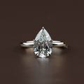 2 carat pear cut lab grown diamond set in a 14k yellow gold lotus petal setting on a whisper thin dainty band showing high brilliance and icy white light return.