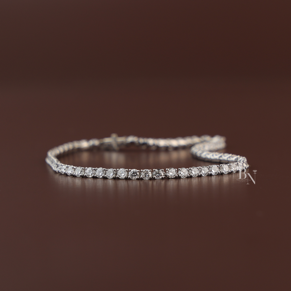Four carat total weight round brilliant cut lab grown diamond inline tennis bracelet in a solid 14k white gold four prong link setting with an integrated security clasp shown draped over a hand.