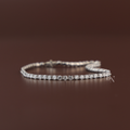 Four carat total weight round brilliant cut lab grown diamond inline tennis bracelet in a solid 14k white gold four prong link setting with an integrated security clasp shown draped over a hand.