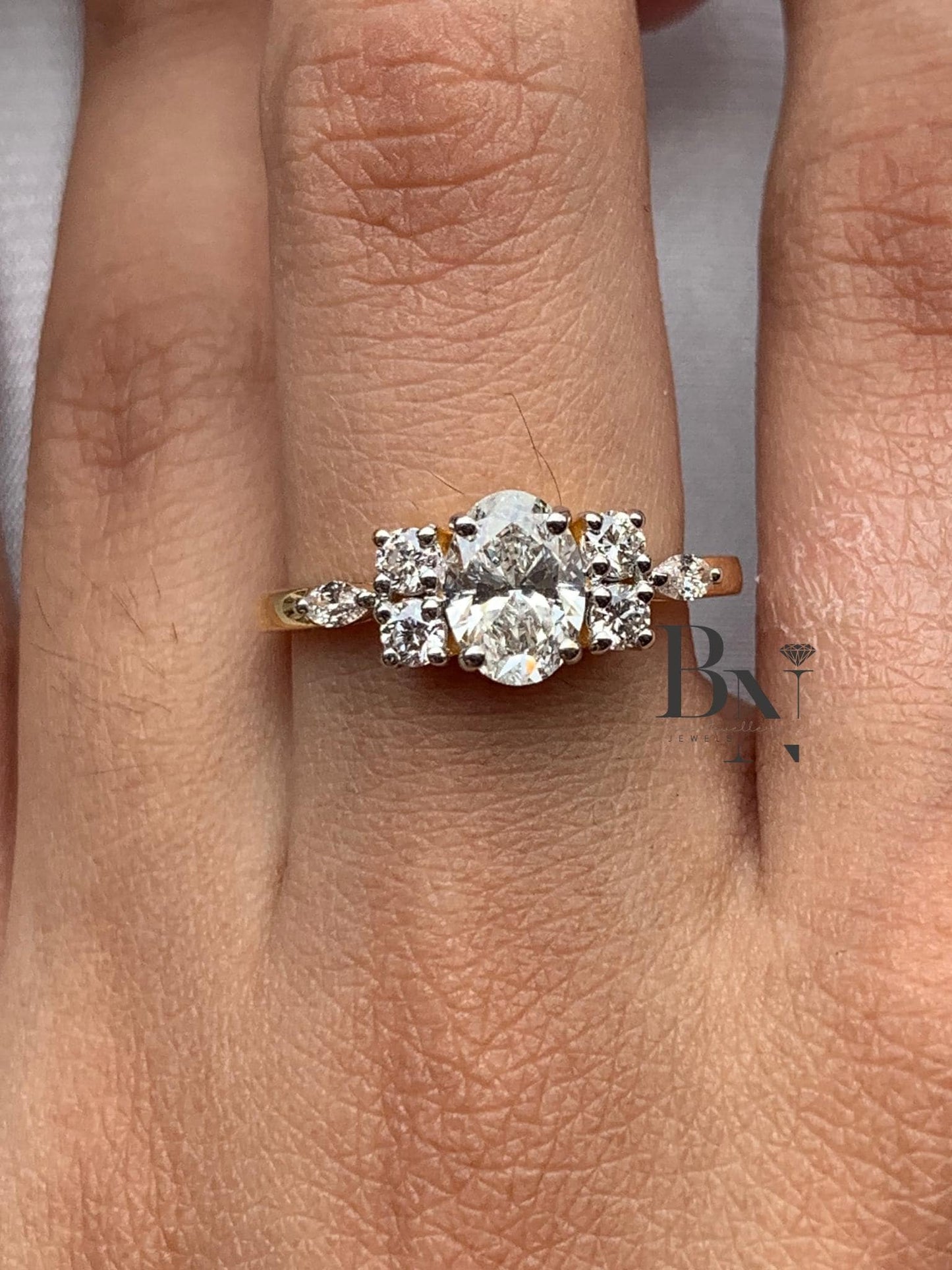 Hand modeling a unique oval cluster engagement ring in 14k gold. The center oval diamond is flanked by a spray of round and marquise accent diamonds in a floral, vintage-inspired design