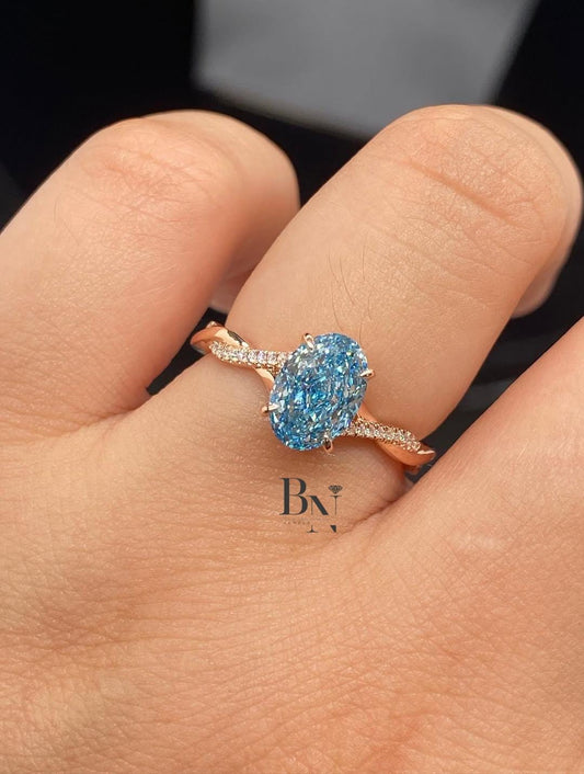 1.50 carat oval blue lab grown diamond engagement ring with a twisted pavé band in a romantic rose gold setting.