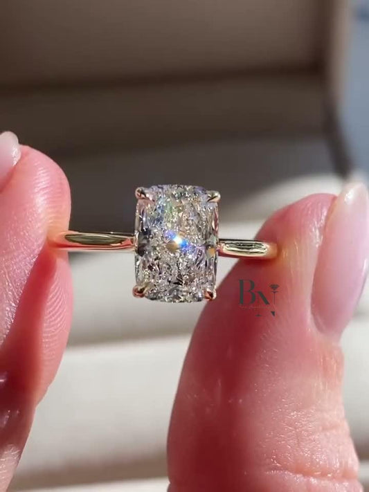 Close-up of a 2 carat elongated cushion lab-grown diamond ring held between two fingers. The video showcases the stone's exceptional clarity and sparkle, set in a classic four-prong solitaire on a polished 14K yellow gold band.