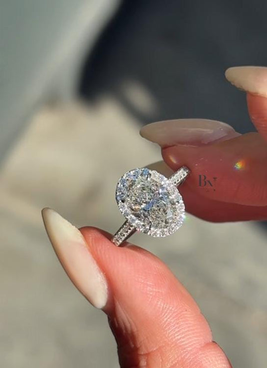 Luxurious 2 carat oval lab grown diamond engagement ring featuring a radiant halo setting and diamond pavé band in polished white gold finish.