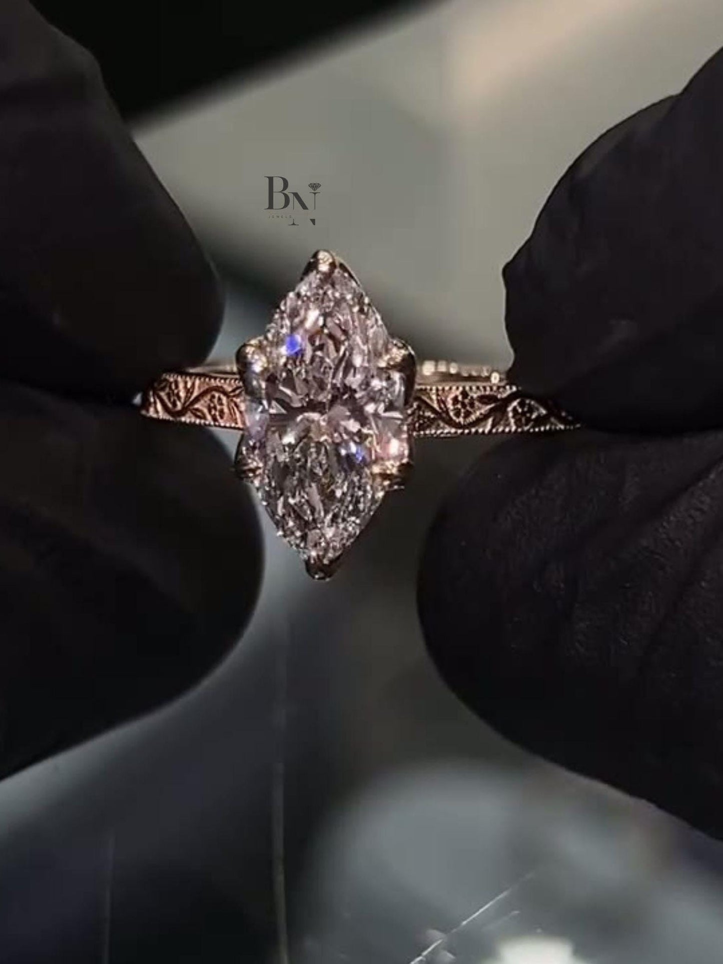 Detailed view of a 2 carat marquise lab grown diamond engagement ring with a vintage hand-engraved scroll band in 14k gold. Luxury bridal.