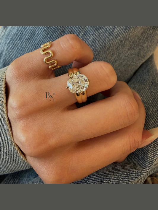 Close up view of a 3 carat elongated Old Mine Cut (OMC) lab grown diamond solitaire ring featuring a bold, chunky 14k yellow gold wide band. The vintage-style cushion stone with authentic chunky facets is secured by sharp claw prongs, creating a modern yet antique-inspired luxury engagement ring.