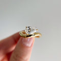 Hand-model view of 1.75 carat Pear Cut Lab Grown Diamond ring with a sleek, chunky swirl bypass setting in high-polished yellow gold, showcasing the modern sculptural design.