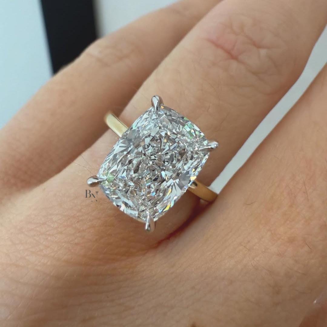 Hand shot of a 3 carat elongated cushion cut moissanite engagement ring with crushed ice effect, set in two-tone gold, showing high fire and maximum visual spread.