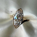 Macro shot of a large 3.00 carat marquise lab diamond engagement ring in rose gold, featuring a bezel setting with hidden halo detail and a pave twisted bypass band.
