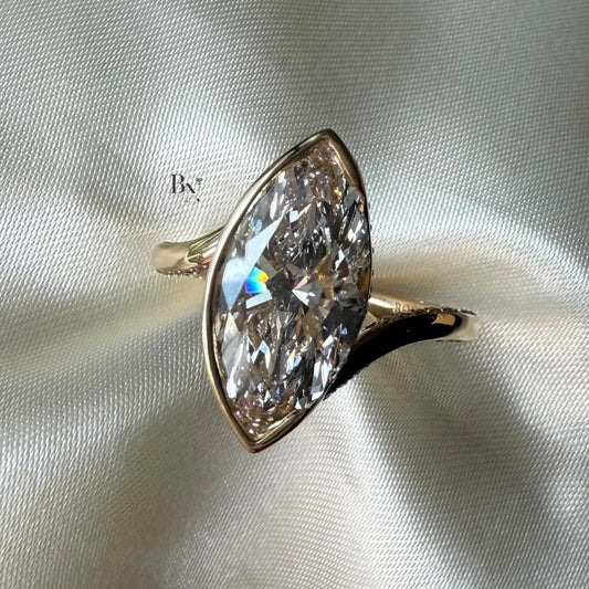 Macro shot of a large 3.00 carat marquise lab diamond engagement ring in rose gold, featuring a bezel setting with hidden halo detail and a pave twisted bypass band.