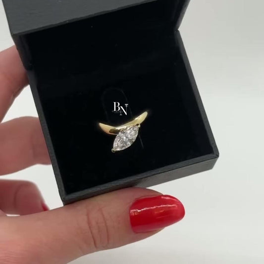 1.00 carat marquise lab diamond engagement ring set east-west in a yellow gold bezel setting, featuring a sculptural bypass wave band.