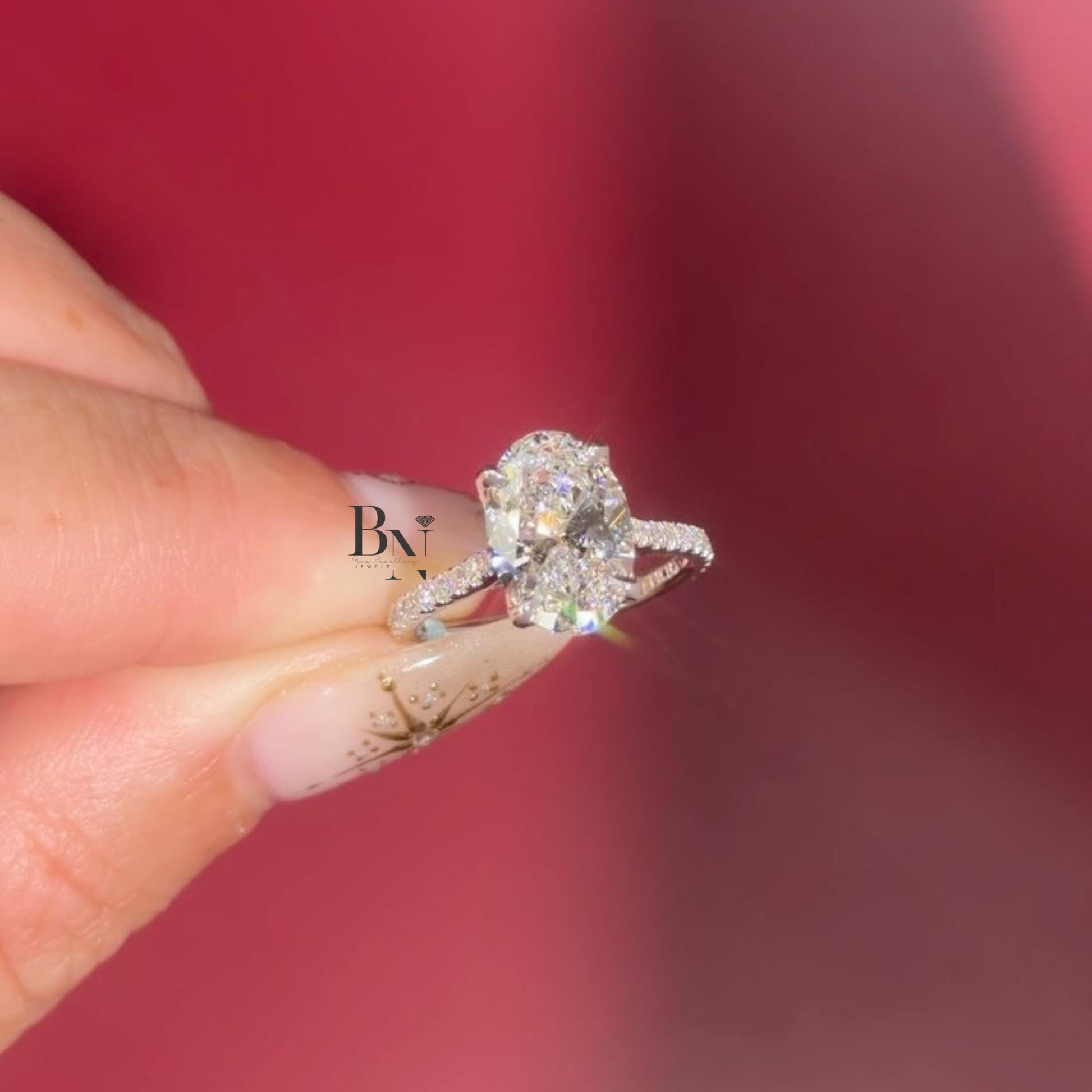 Hand shot of 3 carat oval cut lab grown diamond engagement ring in 14k yellow gold. Solitaire setting with unique marquise dot dash accent pave band. Brilliant cut stone shows maximum white light.