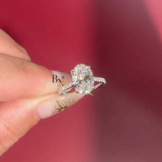 Hand shot of 3 carat oval cut lab grown diamond engagement ring in 14k yellow gold. Solitaire setting with unique marquise dot dash accent pave band. Brilliant cut stone shows maximum white light.