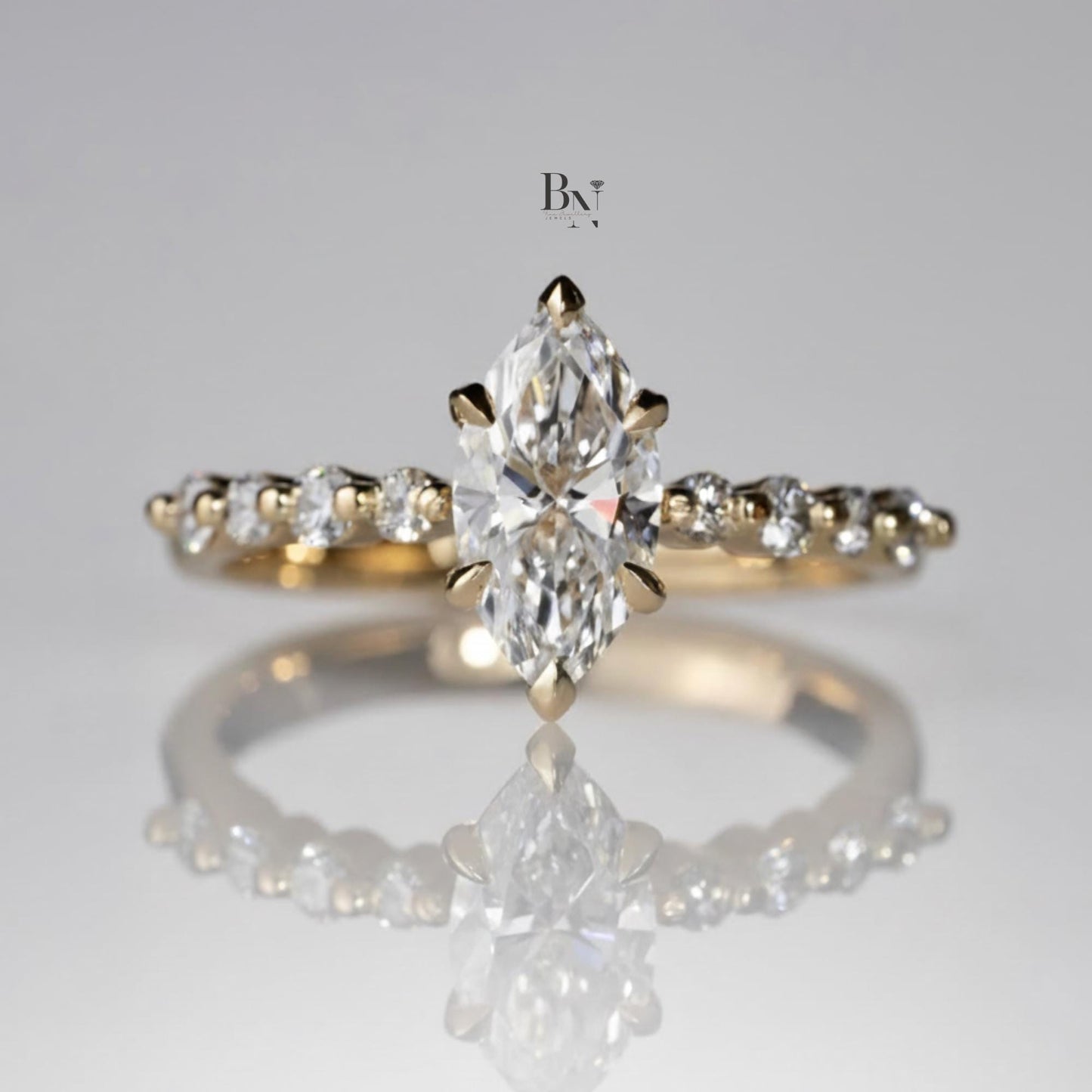Elegant 1.00ct marquise cut lab grown diamond engagement ring in 14k yellow gold. Features a dainty band with graduated round pave accent diamonds and six prongs.