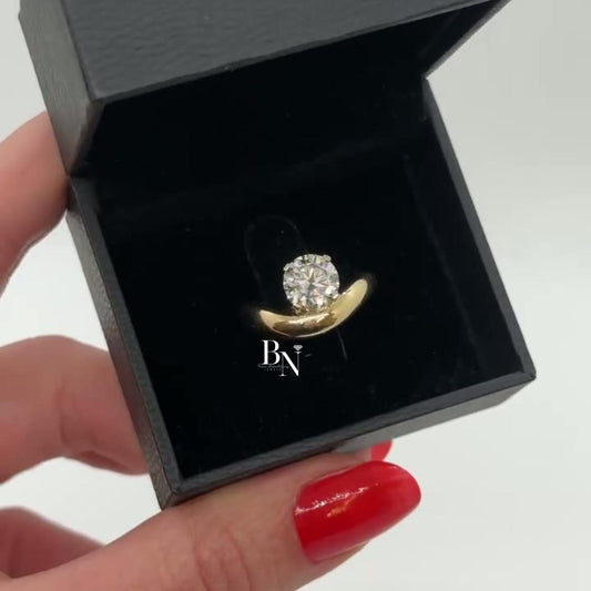 1.00 carat round lab diamond set in a sculptural yellow gold bypass engagement ring, featuring a unique tension-style setting for a sleek, modern look.