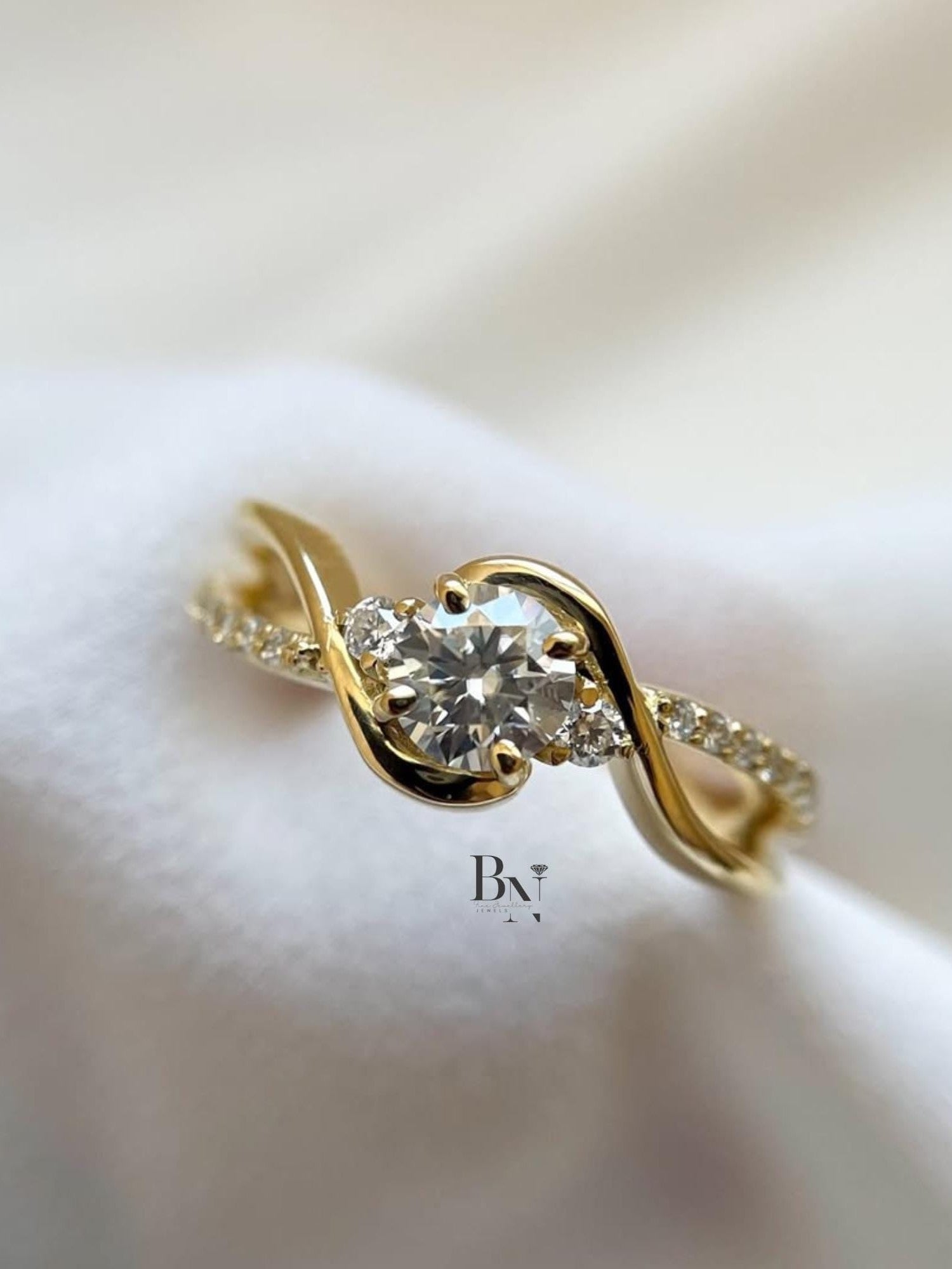 Elegant 1.00ct round brilliant lab grown diamond engagement ring in 14k yellow gold. Features a unique swirl bypass setting with three-stone accents and a micro pave shank.