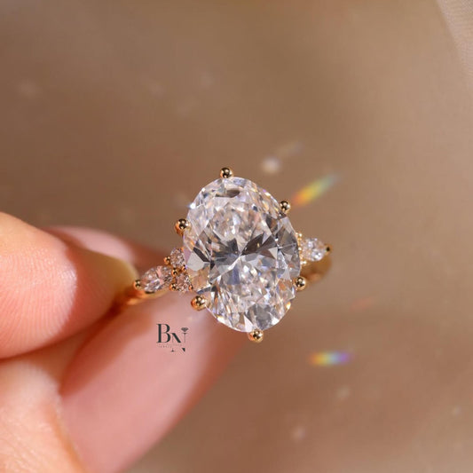 Artistic 3.00ct elongated oval lab grown diamond engagement ring in 14k yellow gold. Features a vine and floral inspired accent band with marquise and round pave diamonds.