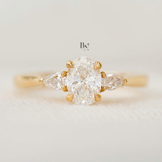 Elegant 1.00ct elongated oval lab grown diamond engagement ring in 14k yellow gold. Features romantic marquise and round dot accent diamonds on the dainty band.