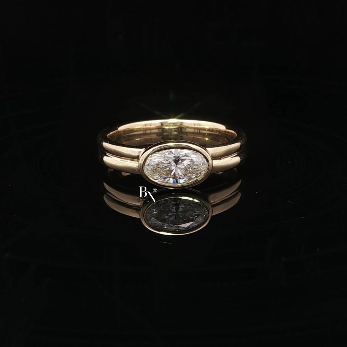 Elegant 1.00ct oval lab grown diamond engagement ring set horizontally (East-West). Secured in a protective full bezel setting with a modern, sculptural double band in 14k yellow gold. A minimalist, quiet luxury statement piece.