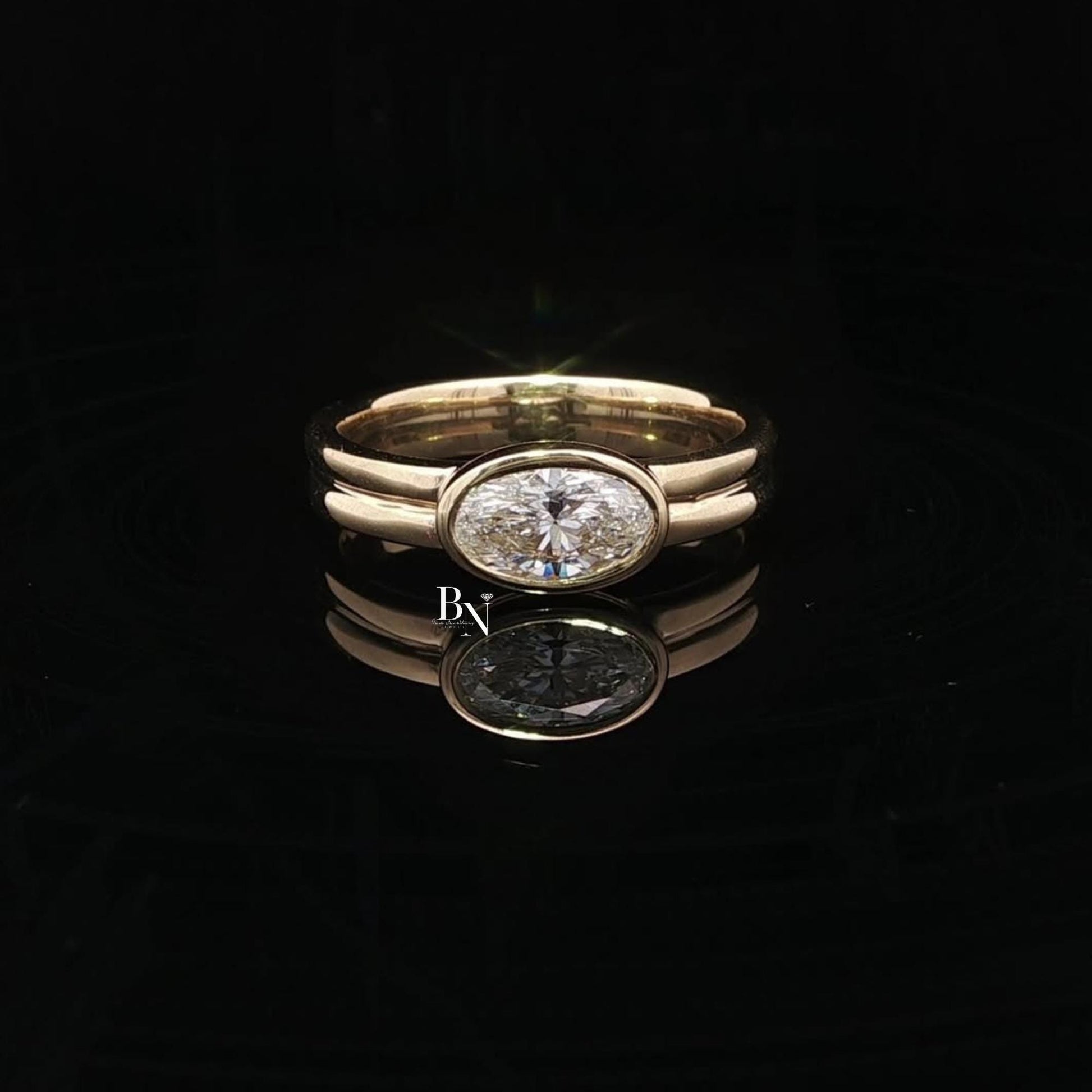 Elegant 1.00ct oval lab grown diamond engagement ring set horizontally (East-West). Secured in a protective full bezel setting with a modern, sculptural double band in 14k yellow gold. A minimalist, quiet luxury statement piece.